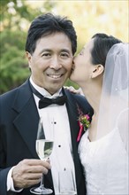 Asian bride kissing groom's cheek