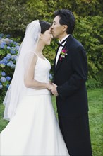 Asian groom kissing bride's forehead