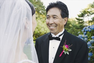 Asian groom smiling at bride