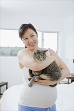 Pregnant Asian woman holding cat