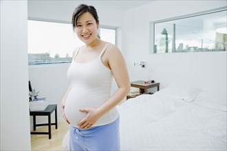 Pregnant Asian woman holding stomach