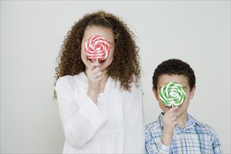 Mixed race brother and sister with oversized lollipops