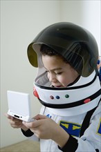 Mixed race boy in astronaut costume with video game