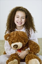 Mixed race girl in nightgown with teddy bear