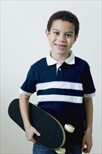 Mixed race boy holding skateboard