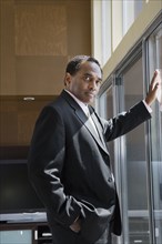 Confident African businessman leaning on glass door