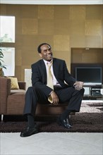 African businessman sitting in modern living room with drink