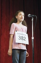 Mixed race girl competing in spelling bee