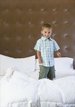 Mixed race boy jumping on bed