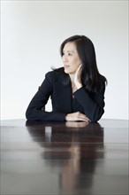 Japanese businesswoman looking pensive at table