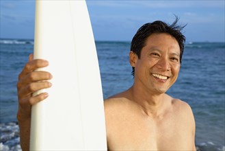 Japanese man with surfboard on beach