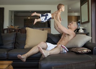 Father lifting son in living room