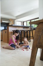 Mother playing with son on floor in kitchen