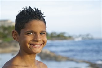 Mixed race boy smiling on beach
