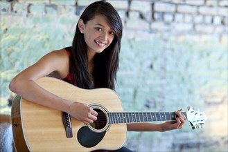 Asian girl strumming guitar