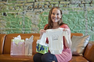 Pregnant Caucasian woman opening baby shower gifts