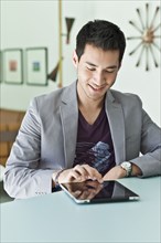 Smiling mixed race man in jacket using digital tablet