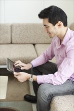 Mixed race man using digital tablet in living room