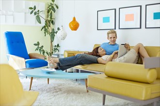 Happy couple relaxing on sofa with digital tablet