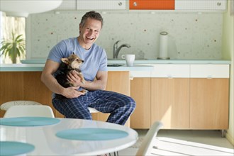 Man sitting in kitchen with dog