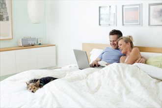 Couple using laptop together in bed