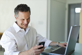 Smiling man text messaging on cell phone