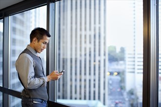 Mixed race businessman using cell phone in office