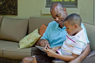 African American father and son using digital tablet