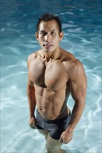 Pacific Islander man standing in swimming pool