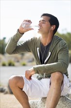 Mixed race man drinking water after exercise