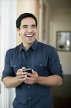 Mixed race man text messaging on cell phone