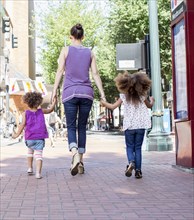 Mother and daughters walking on city street