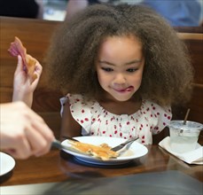 Mixed race girl eating breakfast in restaurant