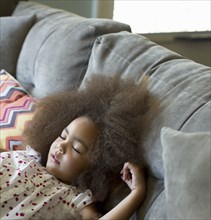 Mixed race girl sleeping on sofa