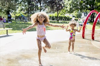 Mixed race girls playing in fountain