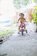 Mixed race girl riding tricycle