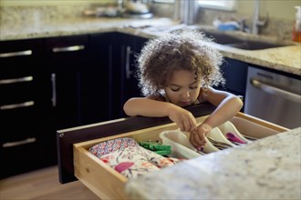 Mixed race girl opening kitchen drawer