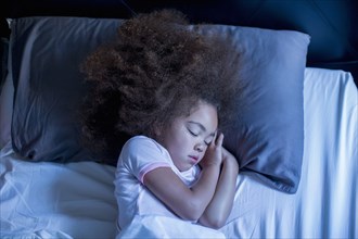 Mixed race girl sleeping in bed