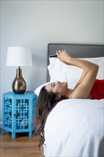 Japanese woman using cell phone on bed