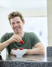 Man eating strawberries in kitchen