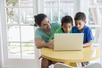Hispanic father and sons using laptop