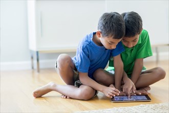 Boys using digital tablet on floor