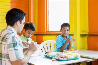 Hispanic boys eating with father in restaurant