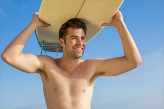 Caucasian man carrying surfboard