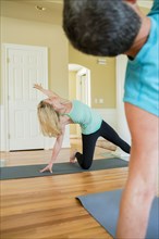 Caucasian people practicing yoga in home