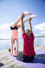 Caucasian couple practicing acroyoga on wooden dock