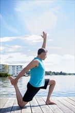 Caucasian man practicing yoga on wooden dock