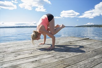 Caucasian woman practicing yoga on wooden dock