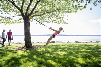 Caucasian woman using exercise bands on tree