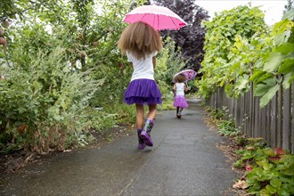 Mixed race girls carrying umbrellas outdoors